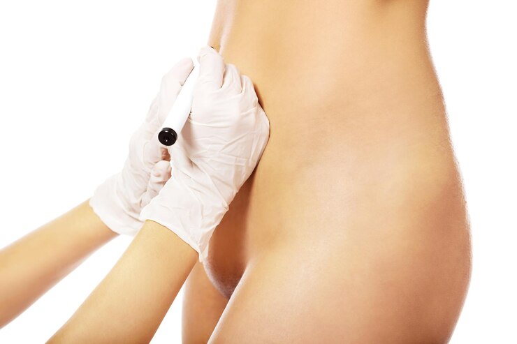 Foto la mano cortada del médico marcando a una paciente desnuda contra un fondo blanco.