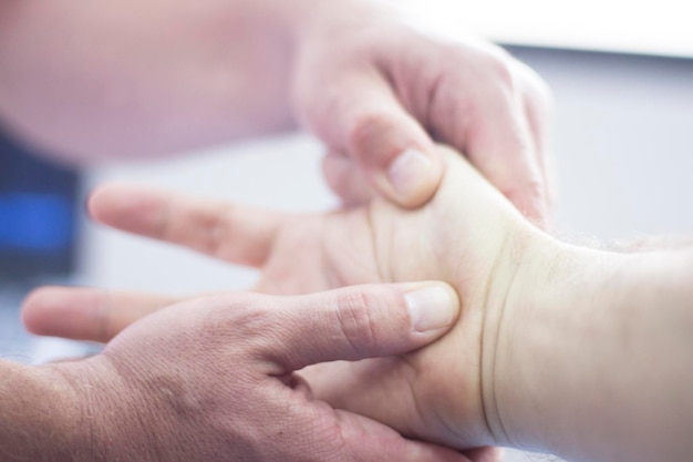 Mano cortada de un médico sosteniendo la mano de un paciente en un hospital