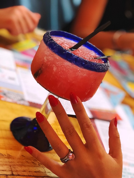 Foto la mano cortada de la mujer por la bebida en la mesa