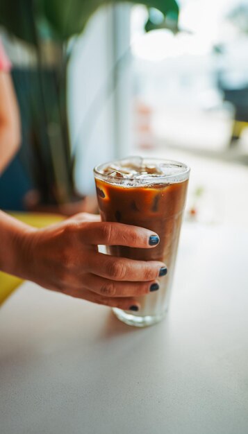 Foto mano cortada de una mujer con bebida en la mesa