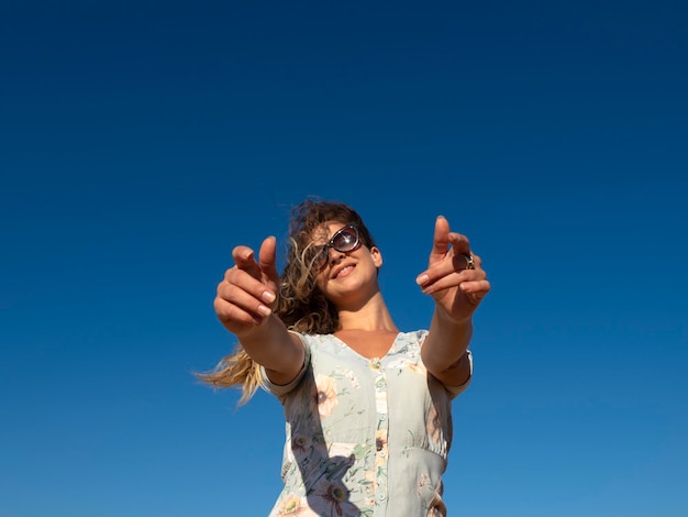 Foto la mano cortada de una mujer con los brazos levantados contra el cielo azul claro