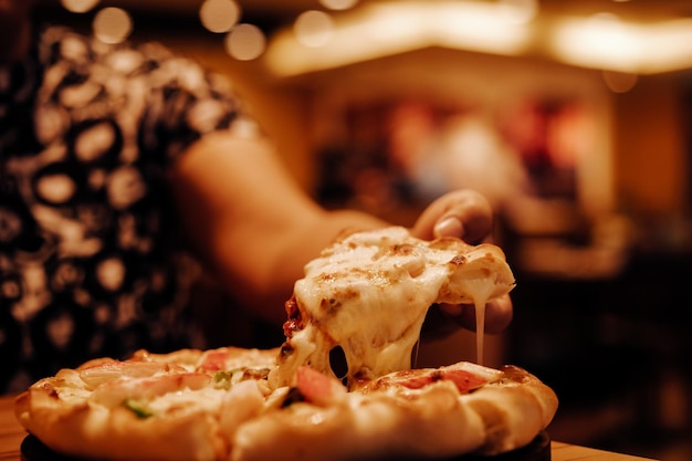 La mano cortada de una mujer comiendo pizza