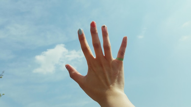 La mano cortada de una mujer contra el cielo