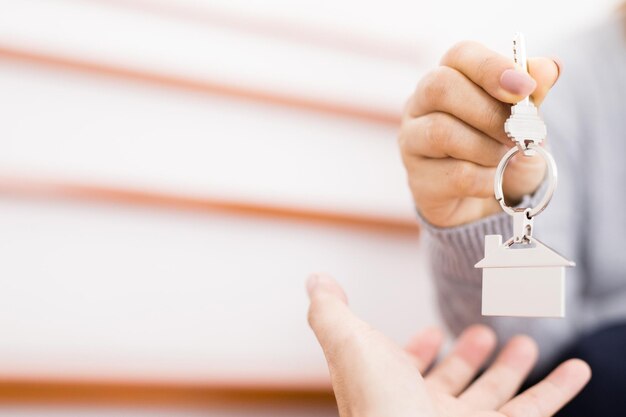 Foto mano cortada de una mujer dando la llave de la casa al cliente