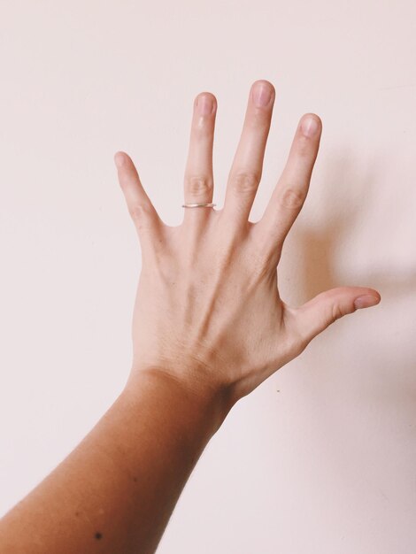 Foto mano cortada de una mujer gestando una señal de alto contra la pared