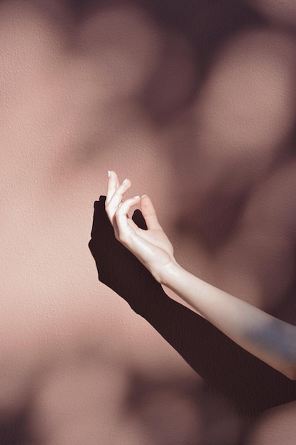 La mano cortada de una mujer haciendo gestos contra la pared