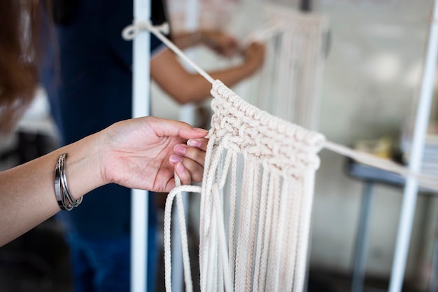 Mano cortada de una mujer haciendo macrame