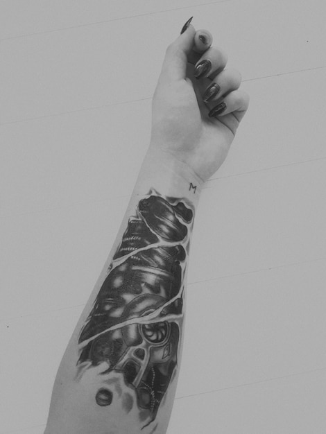 Foto mano cortada de una mujer joven con tatuaje sobre una pared de azulejos