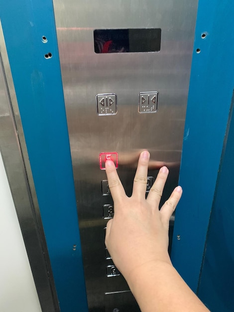 Foto mano cortada de una mujer presionando el botón del ascensor