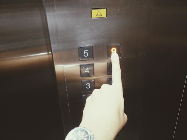Foto mano cortada de una mujer presionando un botón en el ascensor