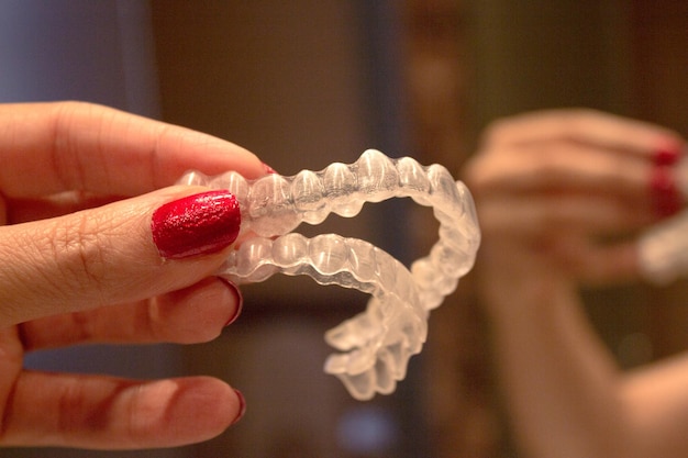 Foto mano cortada de una mujer sosteniendo un alineador dental