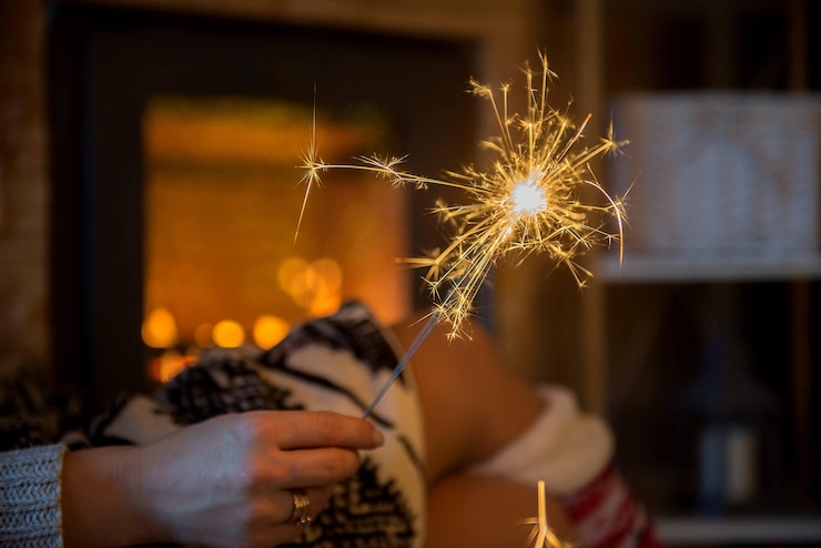 Foto la mano cortada de una mujer sosteniendo una chispa encendida en el cuarto oscuro