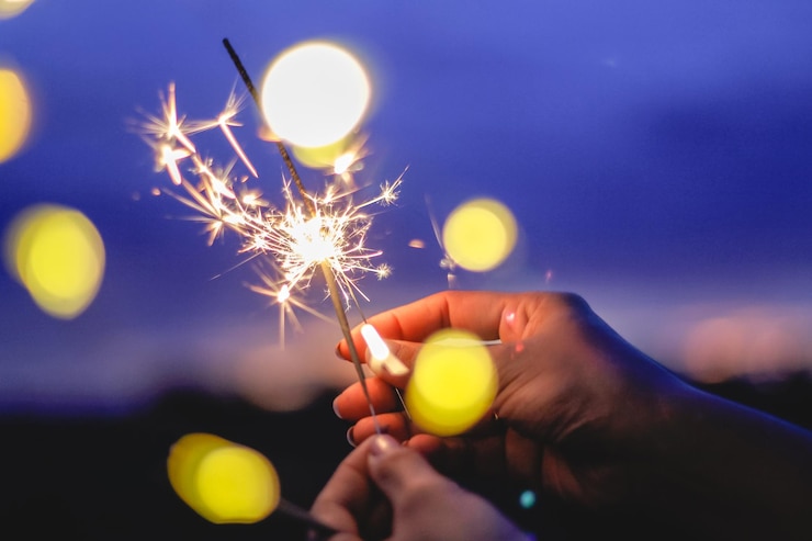 Foto la mano cortada de una mujer sosteniendo una chispa encendida por la noche