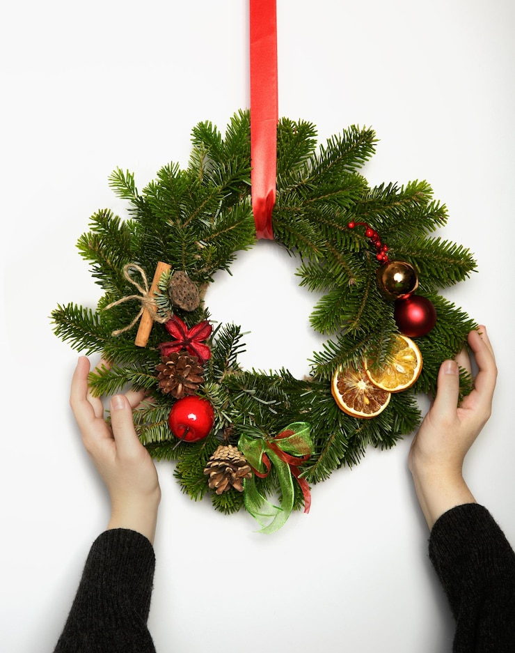 Foto mano cortada de una mujer sosteniendo decoraciones de navidad en la mesa