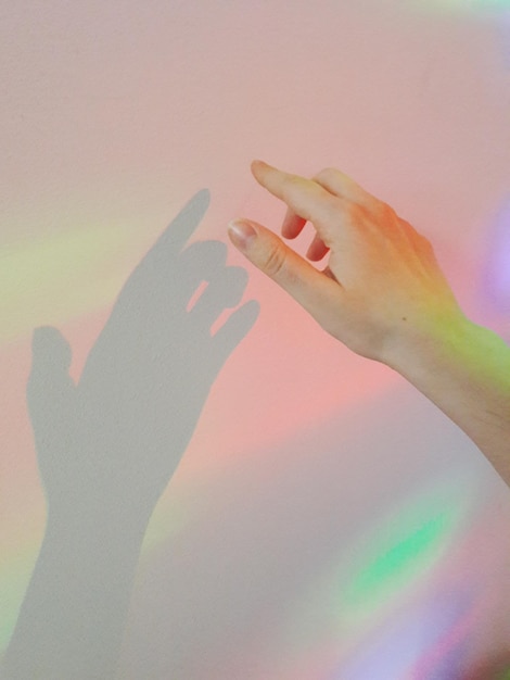 Foto la mano cortada de una mujer tocando una pared iluminada