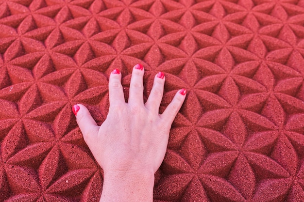 Foto mano cortada de una mujer tocando una pared roja con patrones