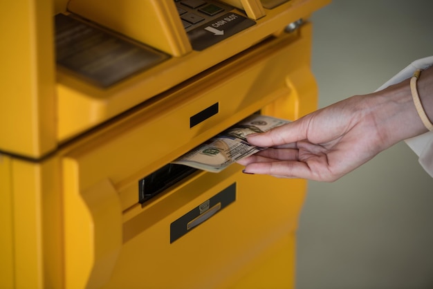 Foto mano cortada de una mujer usando un cajero automático