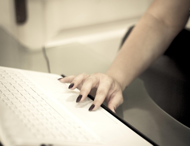 Foto mano cortada de una mujer usando una computadora portátil en casa