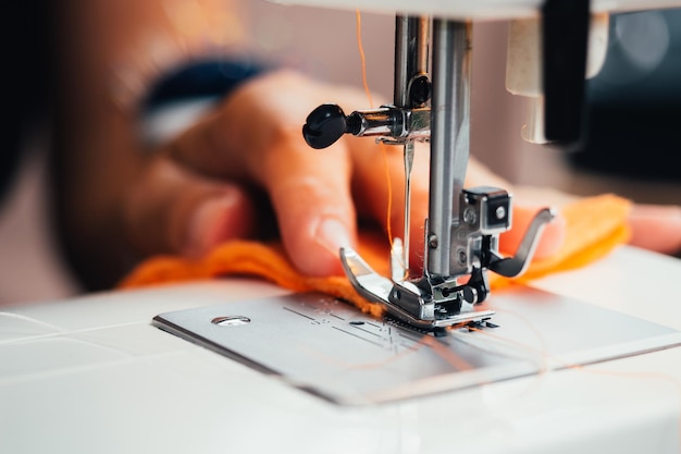 Mano cortada de una mujer usando una máquina de coser en el taller