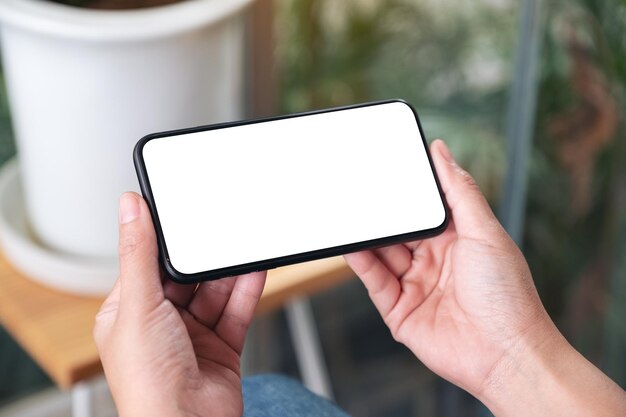 Foto mano cortada de una mujer usando un teléfono inteligente en el interior