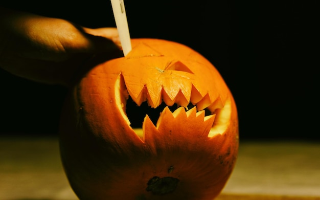 Mano cortada de una persona cortando calabaza durante Halloween