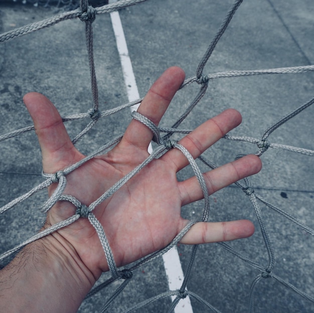 Foto mano cortada de una persona enredada en la red