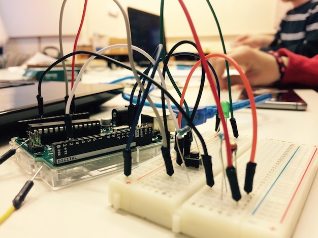 Mano cortada de una persona con equipos eléctricos en la mesa