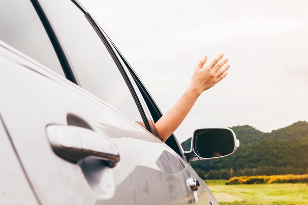 Foto mano cortada de una persona gestando mientras saca la mano del coche en la carretera contra el cielo