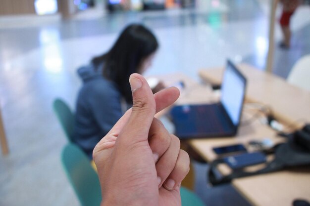 Foto mano cortada de una persona gesticulando contra una mujer sentada en un escritorio en la oficina