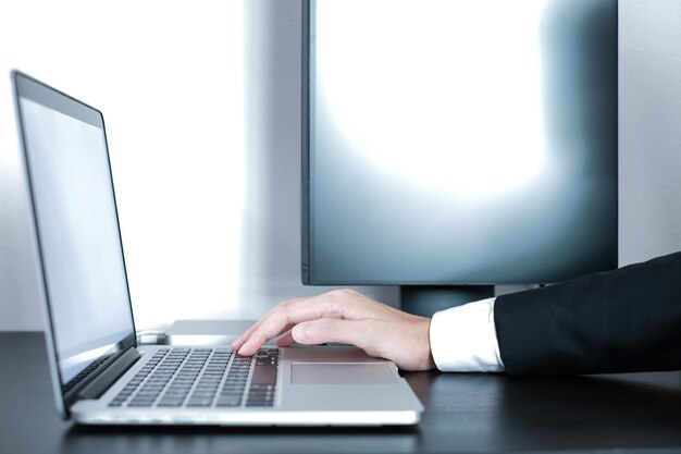 Mano cortada de una persona de negocios usando una computadora portátil en la oficina
