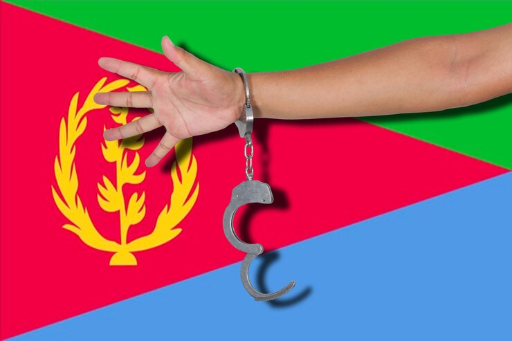 Foto mano cortada de una persona que lleva esposas contra la bandera de eritrea