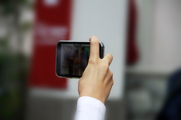 Foto mano cortada de una persona que sostiene un teléfono inteligente