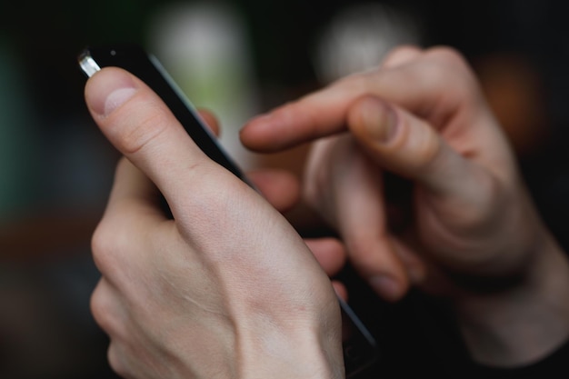 Mano cortada de una persona que usa un teléfono móvil