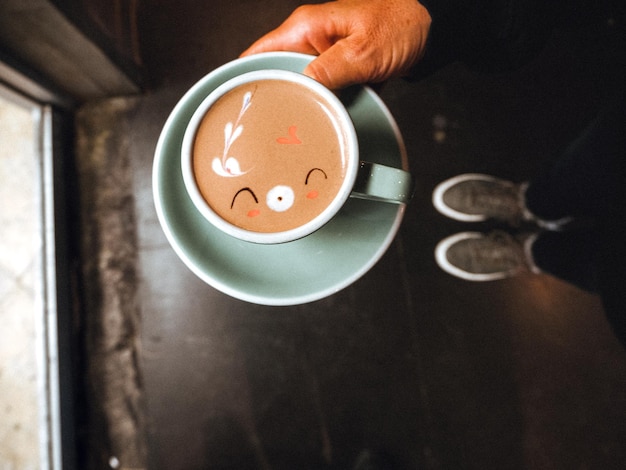 La mano cortada de una persona sosteniendo café.