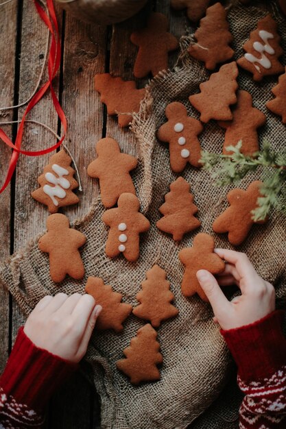 Mano cortada de una persona sosteniendo decoraciones navideñas en la mesa