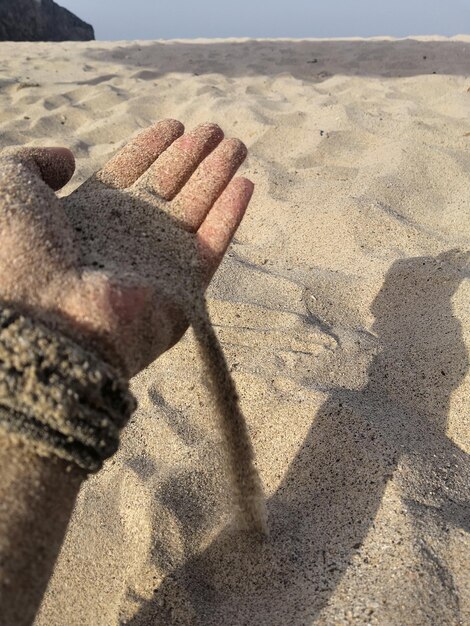 Foto mano cortada en una playa de arena