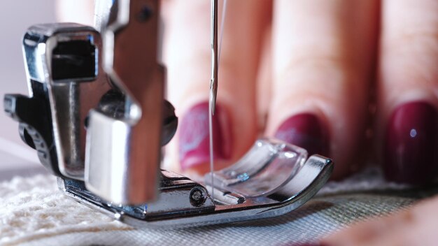 Foto mano cortada de sastre usando la máquina de coser mientras cosía textil