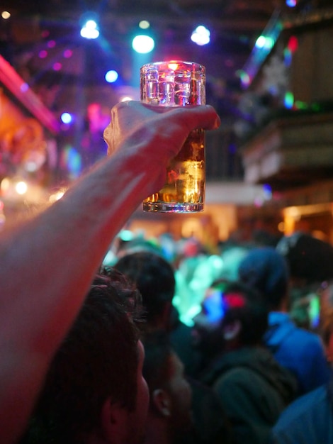 Mano cortada sosteniendo una bebida durante una fiesta