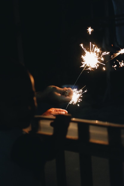 La mano cortada sosteniendo una chispa por la noche