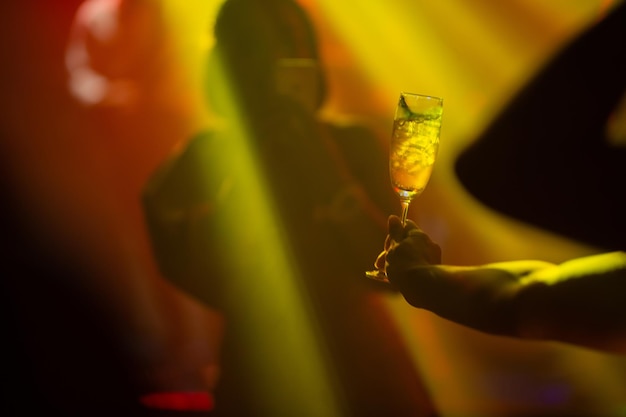 Foto mano cortada sosteniendo copas de vino contra una mujer en una fiesta