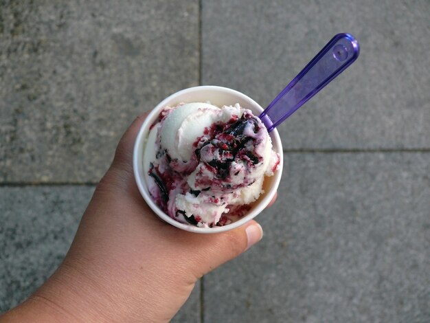 Foto mano cortada sosteniendo helado en el camino