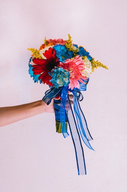 Foto mano cortada sosteniendo un ramo de flores contra un fondo blanco