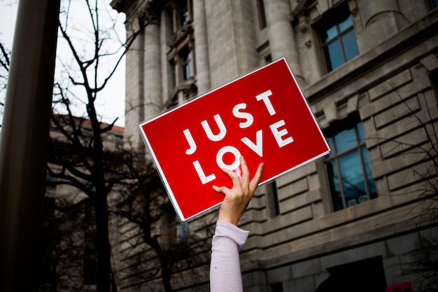 La mano cortada sosteniendo sólo el signo de amor contra el edificio