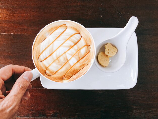 Foto mano cortada sosteniendo una taza de café en una mesa de madera