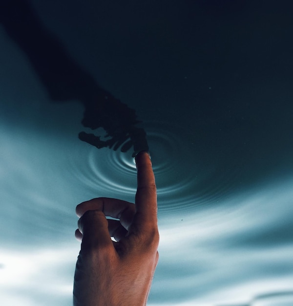 La mano cortada tocando el agua ondulada