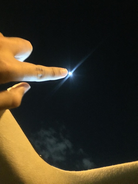 Foto mano cortada tocando el techo del sol del coche por la noche