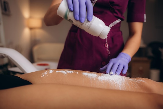 Foto la mano del cosmetólogo está rociando polvo de talco en la axila de una mujer joven antes del procedimiento de depilación depilación y azúcar de la axila foto de alta calidad