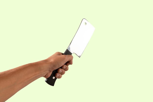 Mano con un cuchillo de carnicero aislado en fondo verde
