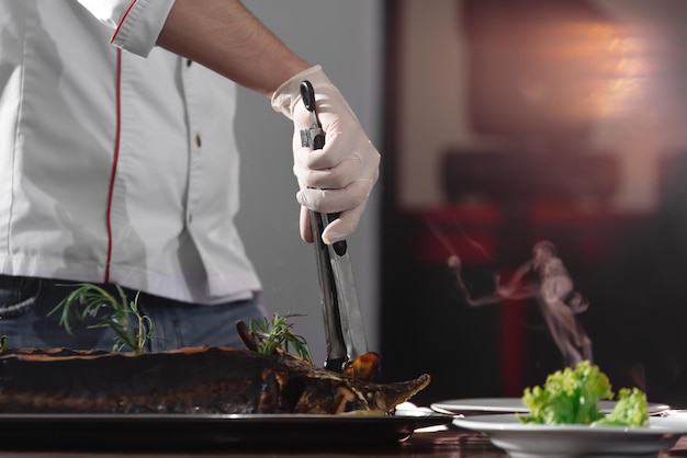 Una mano con un cuchillo corta el pescado bistró chef preparando el almuerzo un chef está cortando un esturión