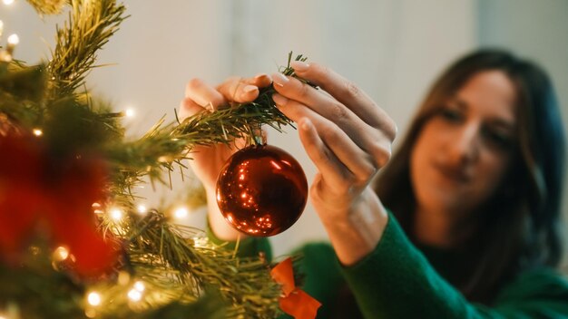 La mano cuelga bolas en el árbol de Navidad